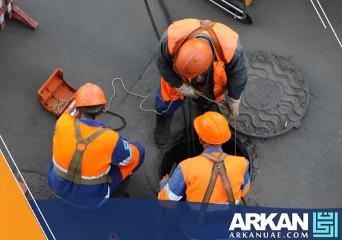 عمال شركة تسليك مجاري في ابوظبي يقومون بصيانة وإصلاح بالوعة صرف صحي بالطريق.