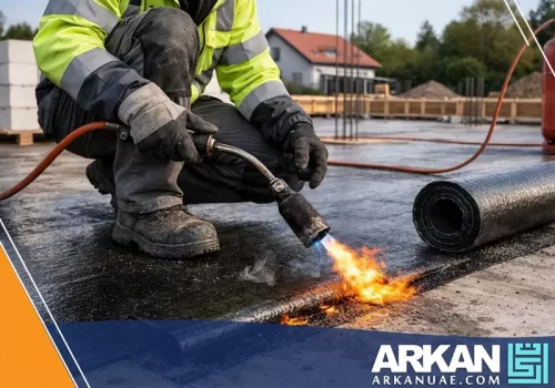 فني افضل شركة عزل اسطح في عجمان يستخدم اللهب لتثبيت لفائف العزل المائي بإتقان.