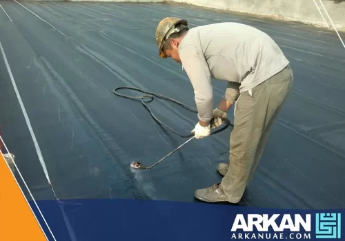فني يقوم بتطبيق عزل الفوم للاسطح في عجمان، مستخدماً معدات رش متخصصة.