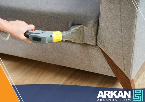 شركة تنظيف بالساعة في عجمان تستخدم معدات متخصصة لتنظيف الأثاث بدقة، باستخدام المكنسة الكهربائية.