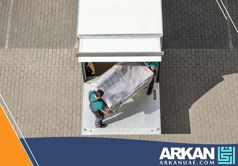 شركة نقل عفش الشارقة 0527514348 أركان التطوير عمال نقل أثاث شركتنا يقومون بحمل قطعة كبيرة بعناية وحرص شديد أثناء إدخالها إلى شاحنة النقل.