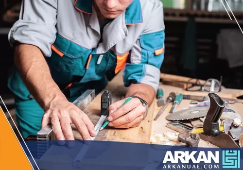 نجار فك وتركيب في دبي وهو يقوم باستخدام الأدوات المناسبة لقياس القطعة الخشبية بدقة عالية.