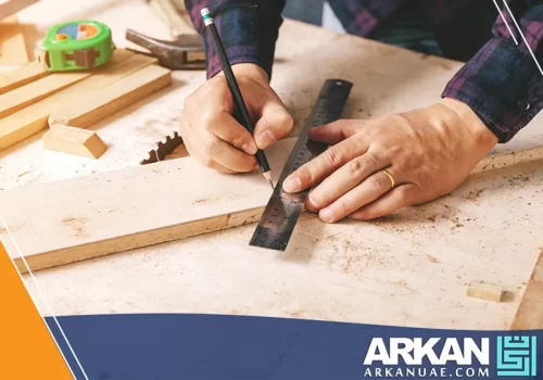 نجار غرف نوم في دبي وهو يعمل على قياس قطعة خشبية باستخدام مسطرة وقلم رصاص.